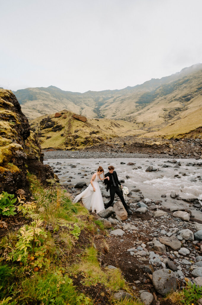 Bride and Groom walking on rocks in Skogafoss Iceland
