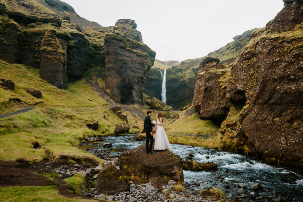 Bride and groom reading vows near waterfall in Skogafoss